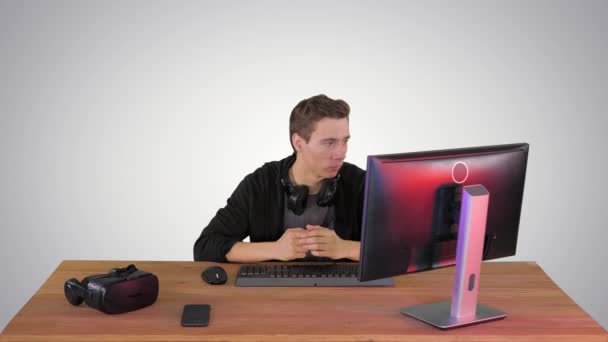 Serious gamer sitting at computer watching a game on gradient background. — Stock Video