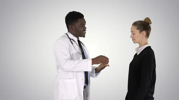 男医生向有梯度背痛的年轻妇女提供药物治疗 — 图库照片