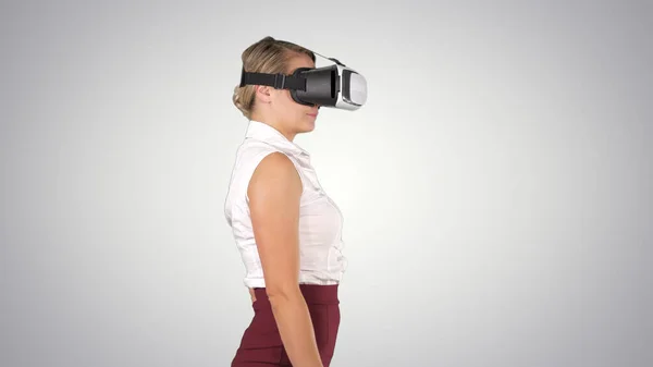 Woman in VR headset walking on gradient background.