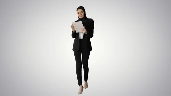 Mujer de negocios árabe en hijab usando tableta mientras walki — Foto de Stock