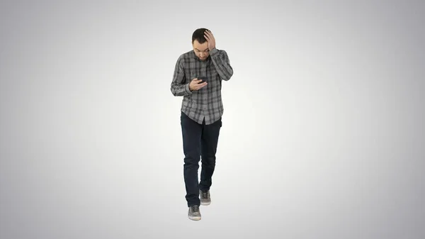 Затиснутий молодий чоловік тримає телефон і читає повідомлення під час ходьби — стокове фото