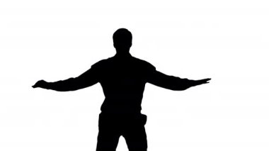 Siluet. Beyaz gömlekli genç adam bükülmüş kollarıyla modern bir dans ediyor..