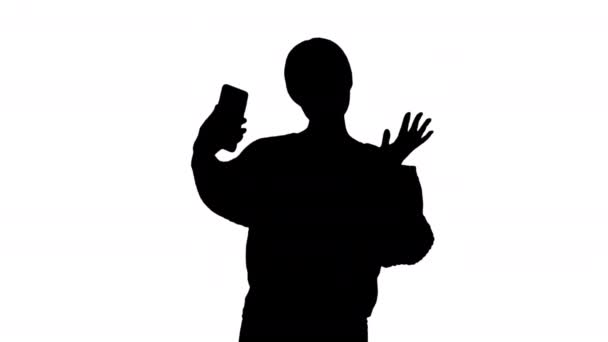 Silhouette Smiling young woman having video call on her phone waving hand. — ストック動画