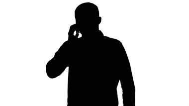 Siluet Genç adam telefonla konuşuyor ve yürüyor.