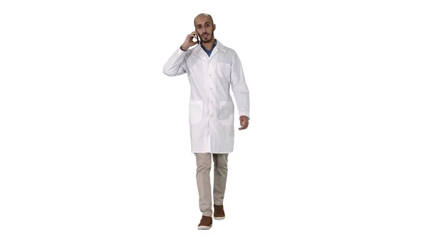 Médico profissional falando no telefone celular enquanto caminhava no fundo branco. — Fotografia de Stock