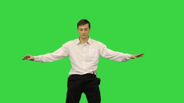 Junger Mann in weißem Hemd tanzt einen modernen Tanz mit gebeugten Armen auf einem Green Screen, Chroma Key. — Stockvideo