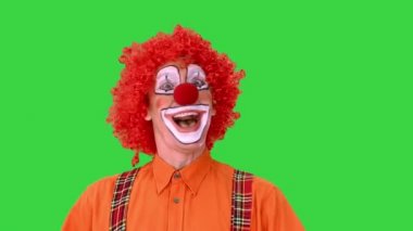 Yeşil Ekran 'ın kenarlarına bakan mutlu yürüyen palyaço, Chroma Key.