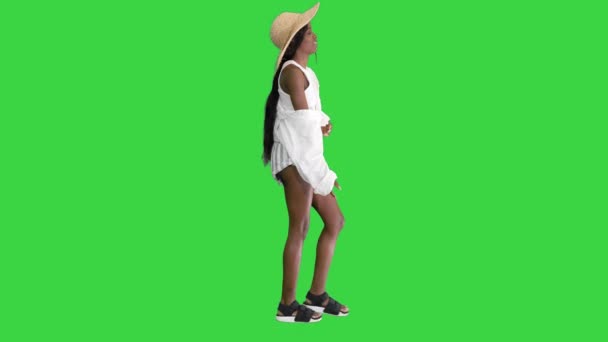 Ragazza afroamericana rilassata che cammina indossando un cappello di paglia e una borsa su uno schermo verde, Chroma Key. — Video Stock