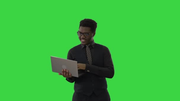 Självsäker afroamerikansk affärsman skriva på laptop och titta på kameran med leende när du står på en grön skärm, Chroma Key. — Stockvideo