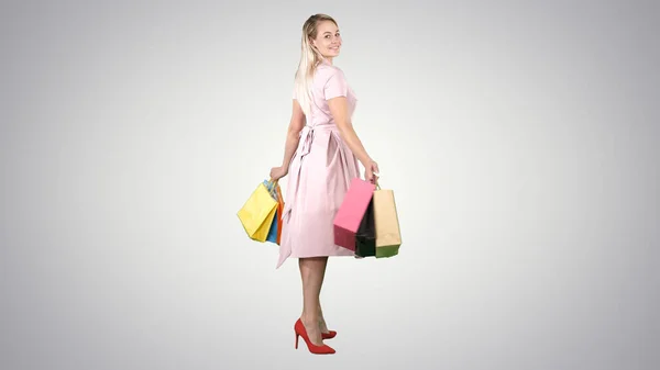 Gelukkige jonge vrouw maakt een bocht met boodschappentassen in haar handen — Stockfoto