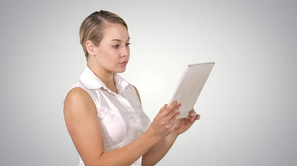 아름다운 여성이 서서 단조 로운 배경에 태블릿을 사용하는 모습. — 스톡 사진