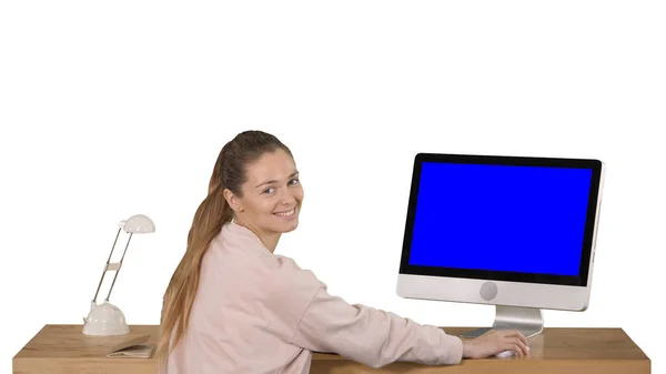 Wesoła kobieta siedząca przy stole z komputerem w biurze i patrząca na aparat uśmiechnięta makieta z niebieskim ekranem Wyświetlacz na białym tle. — Zdjęcie stockowe