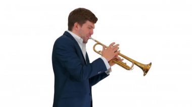 Takım elbiseli genç adam beyaz arka planda yürürken trompet çalıyor..