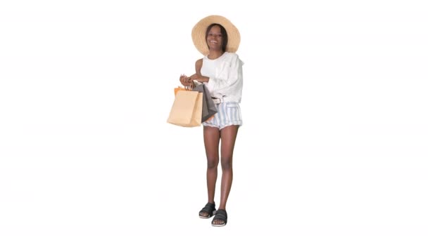 Uśmiechnięta Afroamerykanka w słomkowym kapeluszu, pozująca z torbami na zakupy na białym tle. — Wideo stockowe