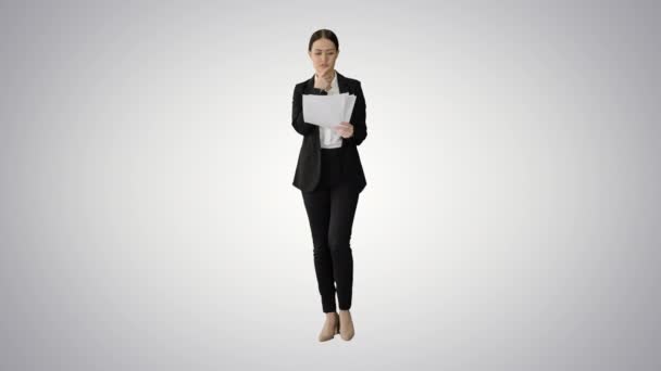 Allvarlig affärskvinna läsa rapport förbereder sig för en presentation när du går på lutning bakgrund. — Stockvideo