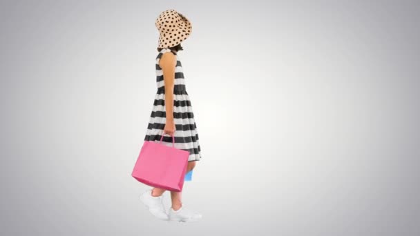 Schattig klein meisje wandelen met boodschappentassen op gradiënt achtergrond. — Stockvideo