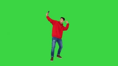 Heyecanlı sıradan adam dans ediyor ve telefonuyla Chroma Key 'de selfie çekiyor..