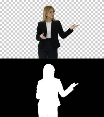 Kadın sunucu, sarışın kadın yürüyor ve kenarları işaret ediyor.,
