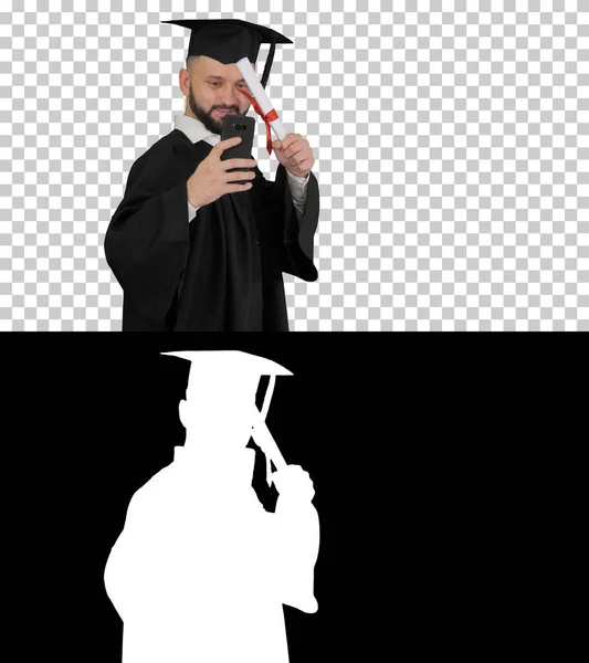 Man wearing the graduation robe walking and taking selfie with d