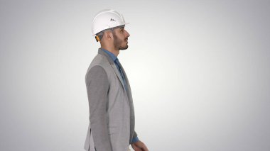 Beyaz miğferli mimar gradyan arkaplanda yürüyor.