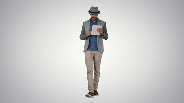 Guapo sonriente árabe hombre en un sombrero caminando y usando la tableta en g —  Fotos de Stock