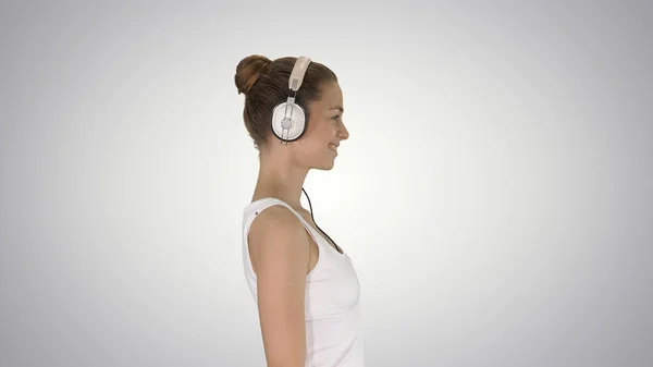 Happy casual girl wearing headphones walking on gradient backgro — Stock Photo, Image