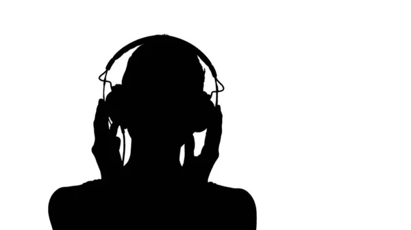 Силуэт Улыбающаяся молодая женщина слушает музыку в наушниках — стоковое фото