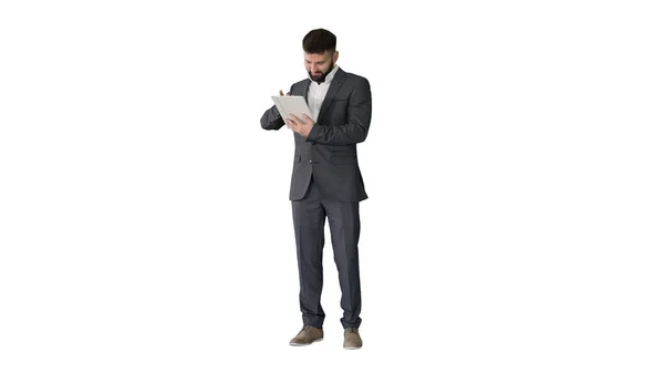 Бизнесмен стоит и использует планшетный компьютер на белой backgrou — стоковое фото