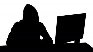 Siluet Kapüşonlu bilgisayar korsanı bilgisayar ve akıllı telefon kullanıyor.