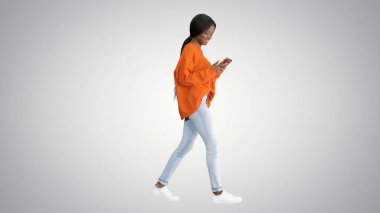 Gülümseyen kadın yürürken telefonuna mesaj yazıyor.