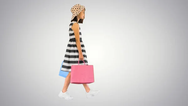 Cute little girl spacery z torbami na gradient backgrou — Zdjęcie stockowe