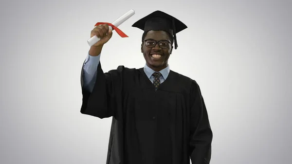 Glad afrikansk amerikansk manlig student i examen mantel promenader t — Stockfoto