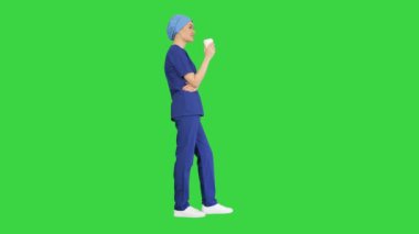 Gülümseyen kadın doktor ya da mavi üniformalı hemşire yeşil ekranda kahve molası veriyor, Chroma Key.