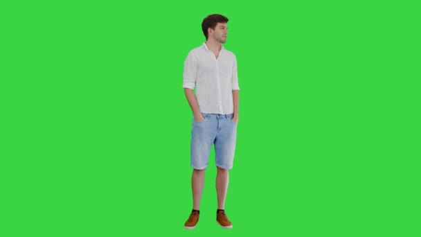 Casual ung man tittar åt sidan och talar om något på en grön skärm, Chroma Key. — Stockvideo