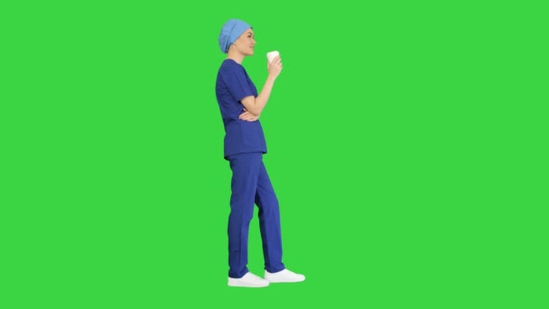 穿着蓝色制服、在绿色屏风上喝咖啡休息的女医生或护士的微笑，铬钥匙. — 图库视频影像