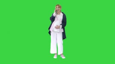 Çekici hamile kadın telefon ediyor ve karnını yeşil ekranda tutuyor, Chroma Key..