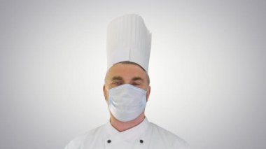 Erkek aşçı, arka plandaki virüs hastalıklarından korunmak için yüz koruyucu maske takıyor..