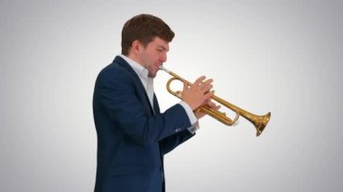 Takım elbiseli genç adam arka planda yürürken trompet çalıyor..