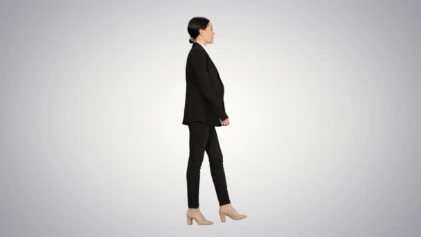 Mujer de negocios segura caminando hacia la cámara con una sonrisa en el fondo del gradiente. — Vídeos de Stock