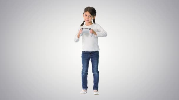Gadis kecil yang bersemangat bermain video game memegang joystick di tangannya pada latar belakang gradien. — Stok Video