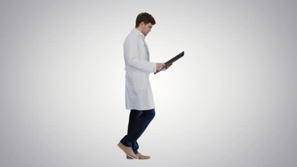 Soustředěný lékař vyšetřující počítačovou tomografii při chůzi na pozadí gradientu. — Stock video