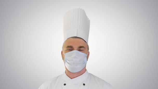 Chef cuisinier masculin portant un masque médical de protection du visage pour la protection contre la maladie virale sur fond de dégradé. — Video