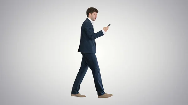 Hombre de negocios serio usando el dial de voz del teléfono mientras que camina en grado — Foto de Stock