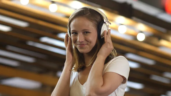 Leuk jong meisje luisteren naar muziek in koptelefoon glimlachen kijken naar camera. — Stockfoto