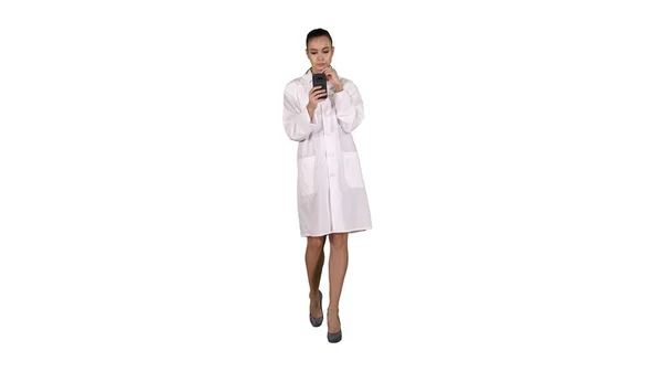 Allegro carino giovane donna medico digitando testo sul telefono mentre a piedi — Foto Stock