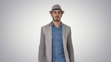 Sıradan bir Arap adam şapkasıyla ve mezuniyet çantasıyla yürüyor.