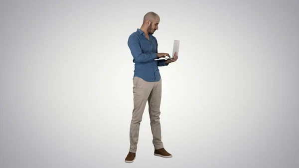 Молодой бизнесмен с Ближнего Востока, стоящий и печатающий на ноутбуке — стоковое фото