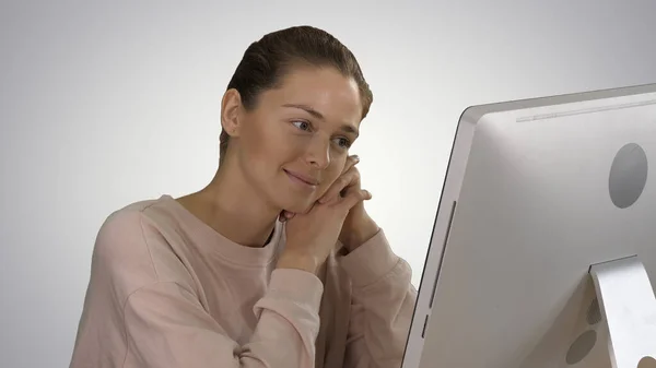 Chica rubia con suéter rosa mirando el monitor de la computadora wa — Foto de Stock