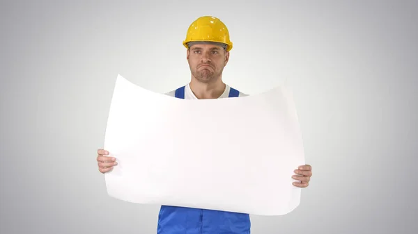 Construction worker checking blueprints on site on gradient back — Stock Photo, Image