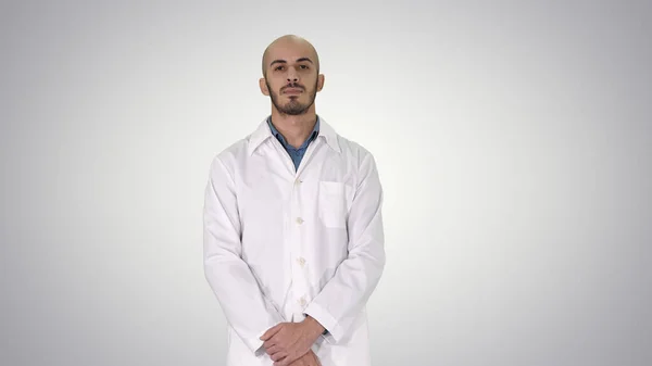 Staande jonge ernstige arabische arts op gradiënt achtergrond. — Stockfoto